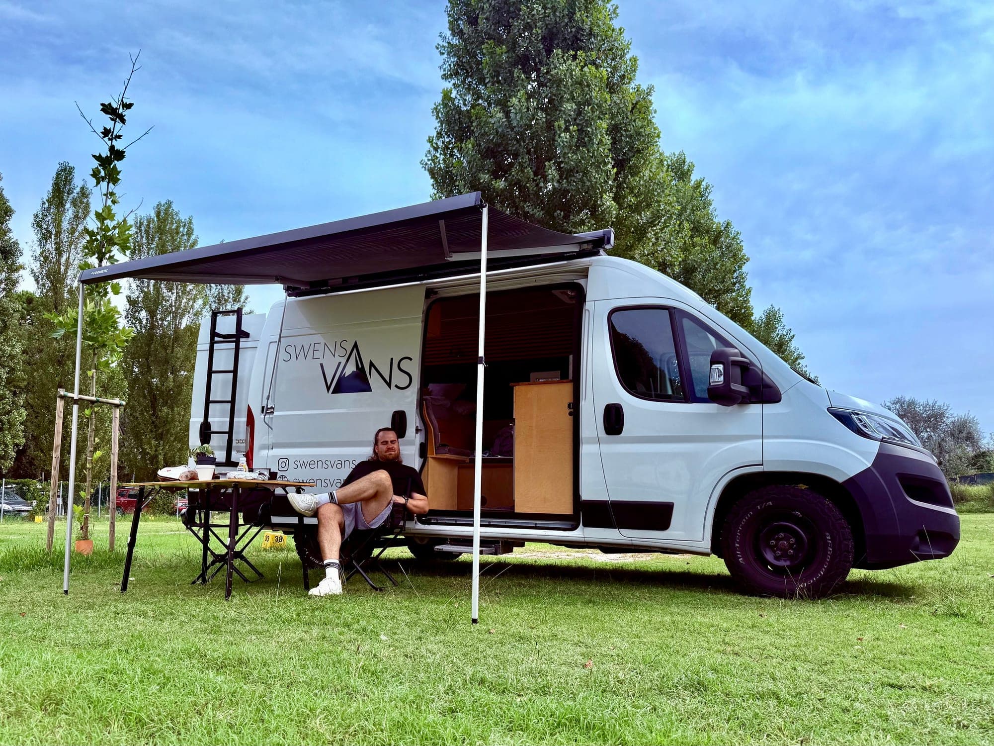SVAN 01 Campervan auf der Wiese mit Markise und gedecktem Tisch