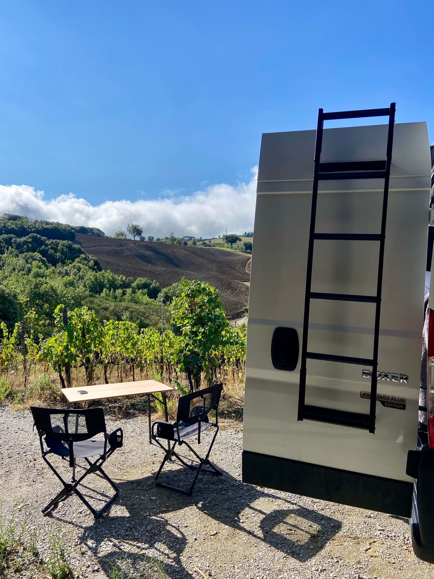 Campingtisch und Stühle neben dem SVAN 01 im Weinberg