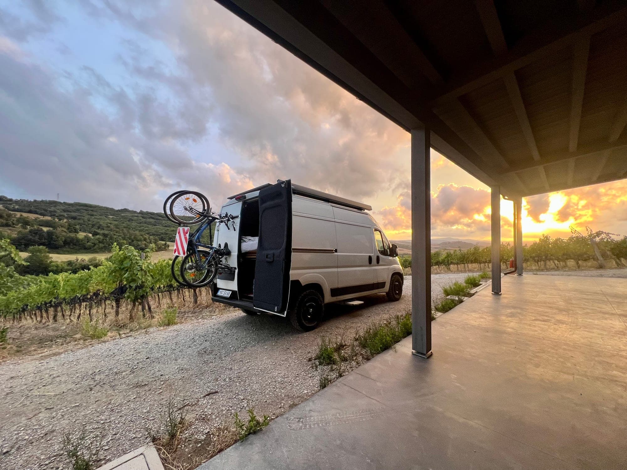 SVAN 01 Campervan am Weinberg bei Sonnenuntergang, Türen offen mit Fahrrädern